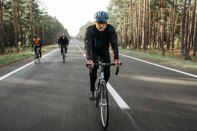 Cyclists riding steadily along a quiet tree-lined road