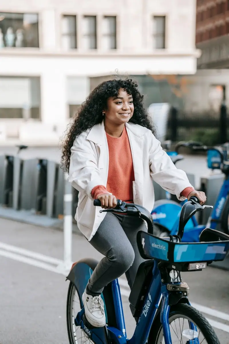 Rider on an electric bike on a city street, both feet on the pedals, moving at a relaxed pace