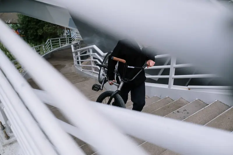 Rider lifting a lightweight electric bike up a flight of stairs, side view